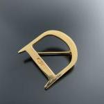 DIOR. BROCHE "D" en métal doré. Signée et monogrammée. 
Hauteur...