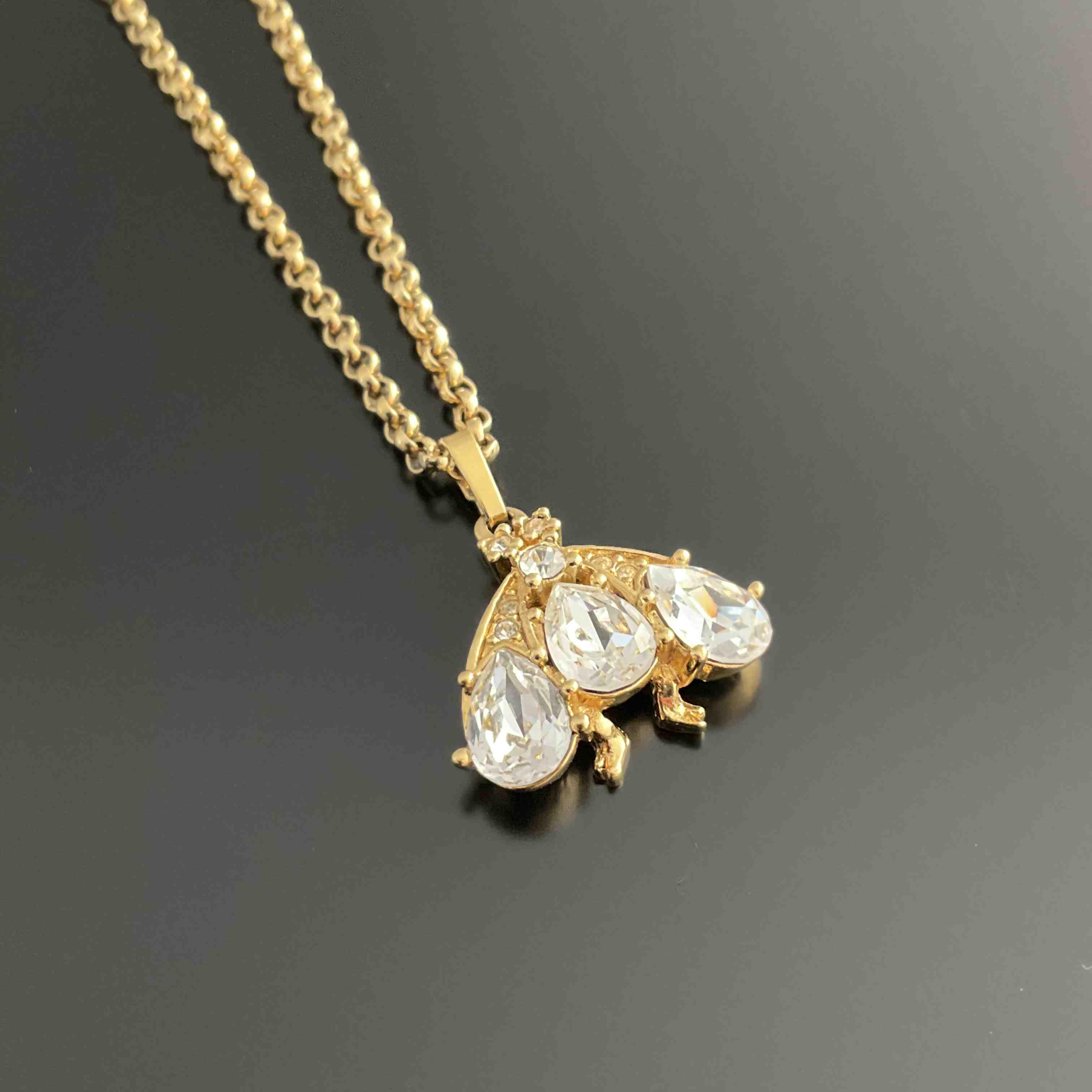 DIOR. PENDENTIF abeille en métal doré et imitations de diamants...